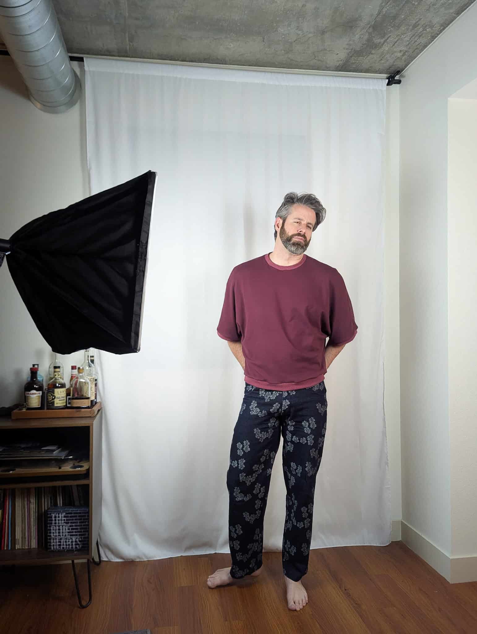 Model standing in a photography studio with a white backdrop, wearing casual loungewear.