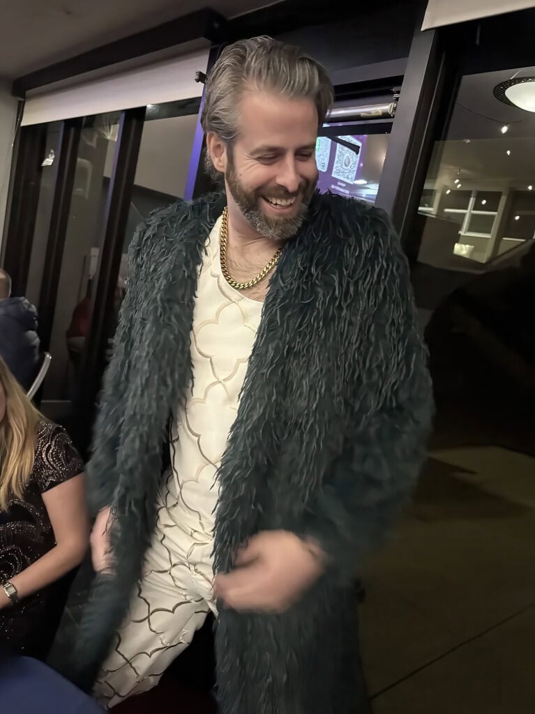 Elegant man wearing a luxurious fur coat at a social gathering.