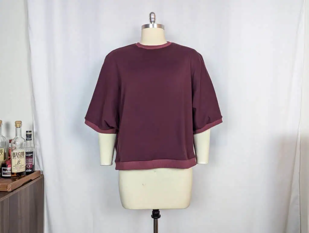 Maroon men's sweatshirt with rolled sleeves and crew neck on mannequin.