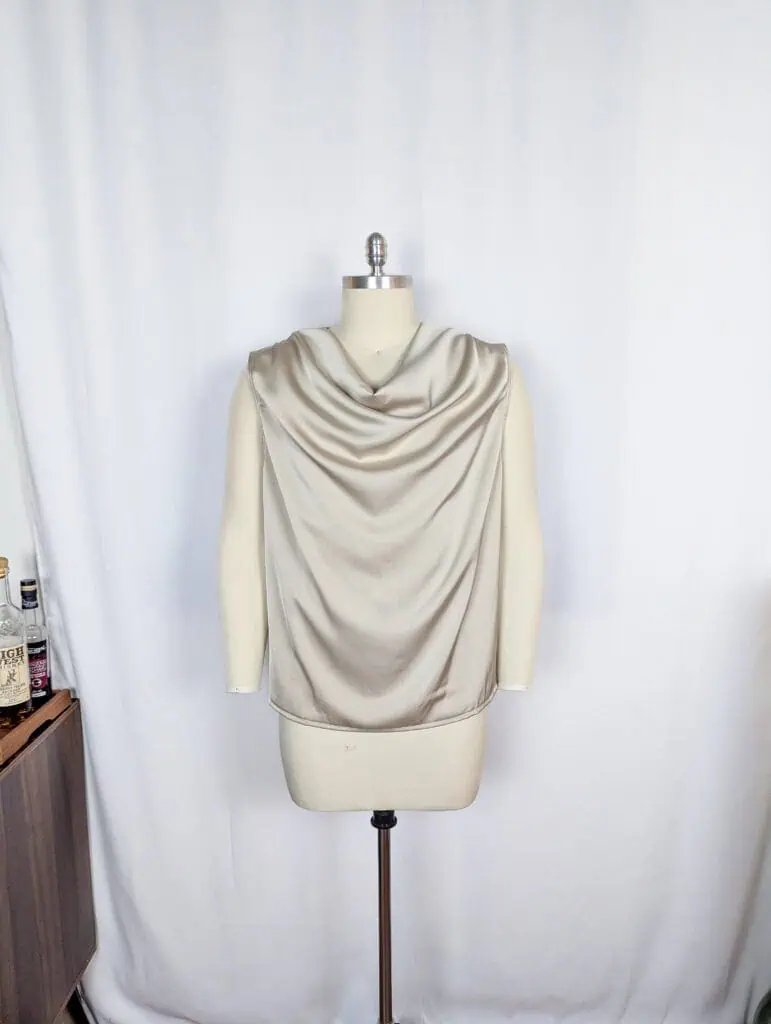 Cream silk sleeveless top with draped neckline on mannequin.