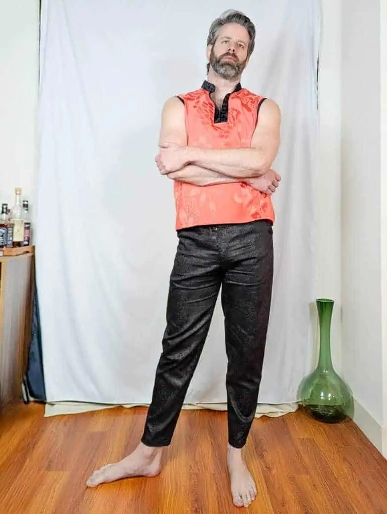 Sleeveless coral men's top with black embroidered collar and front placket.