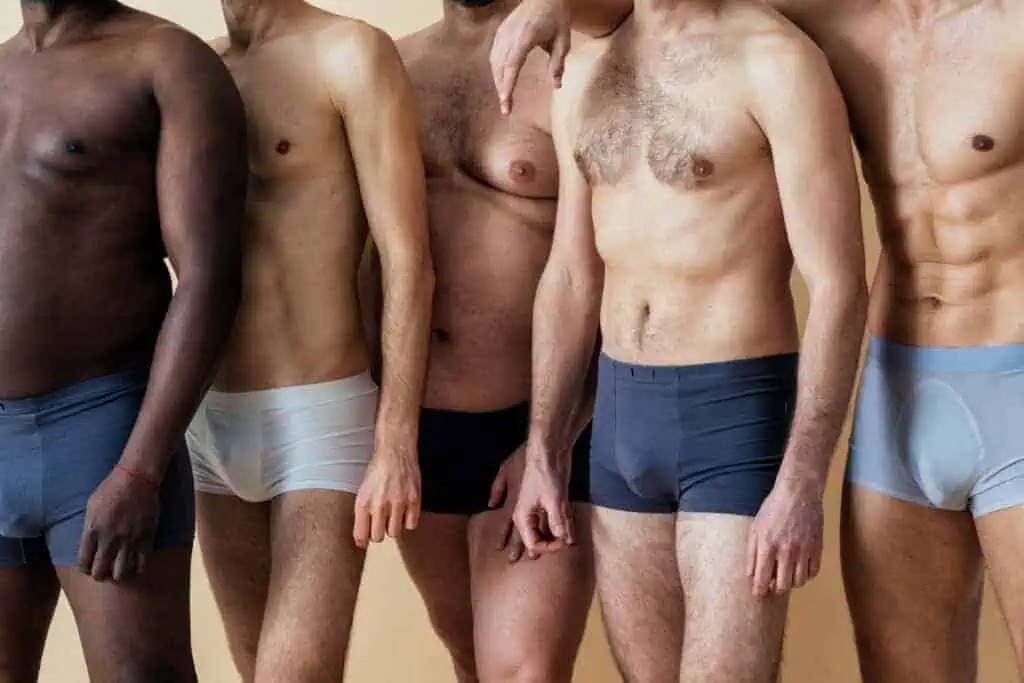 Group of men wearing fitted boxer briefs in various colors and fabrics.