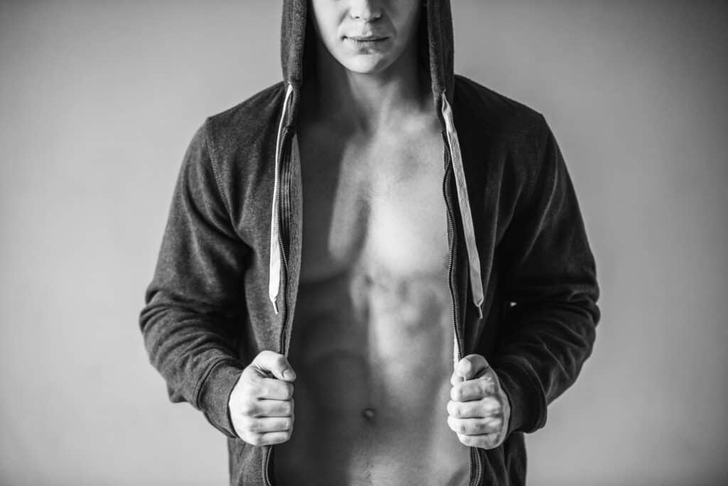 Male model with hoodie open, showing bare chest and abs.