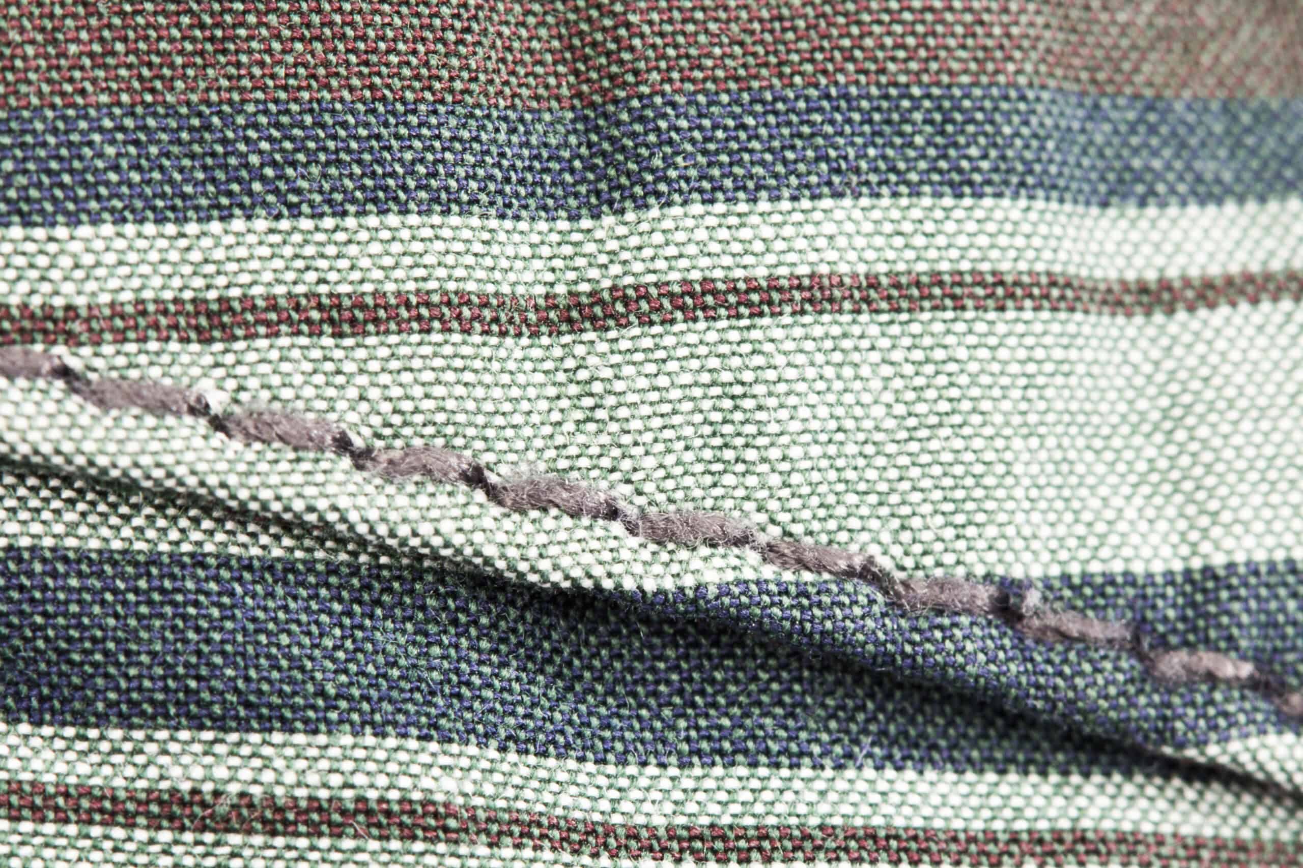 Close-up of hand-stitched fabric seam in striped textile.