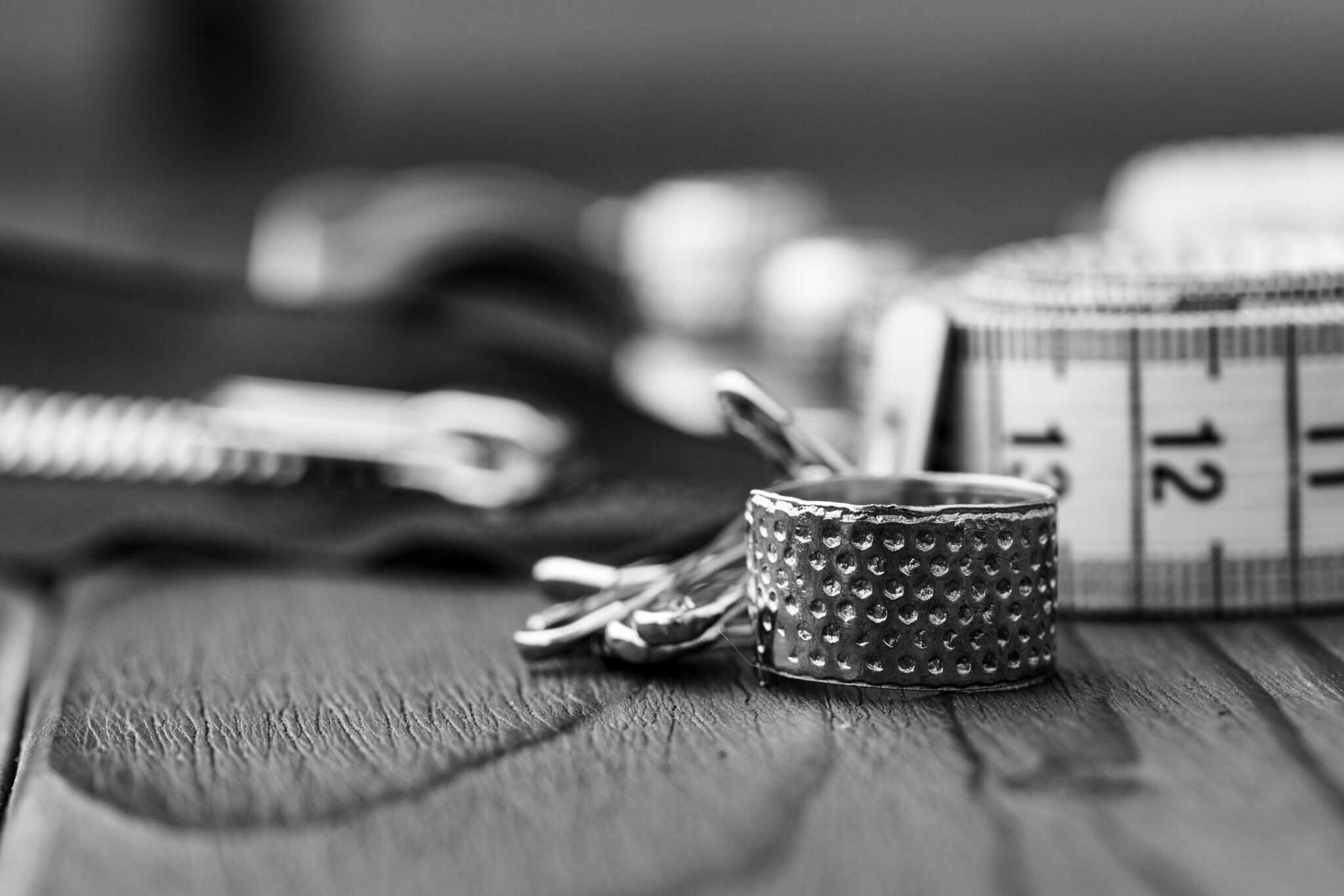 Sewing tools including a measuring tape and wrist cuff on a wooden surface.