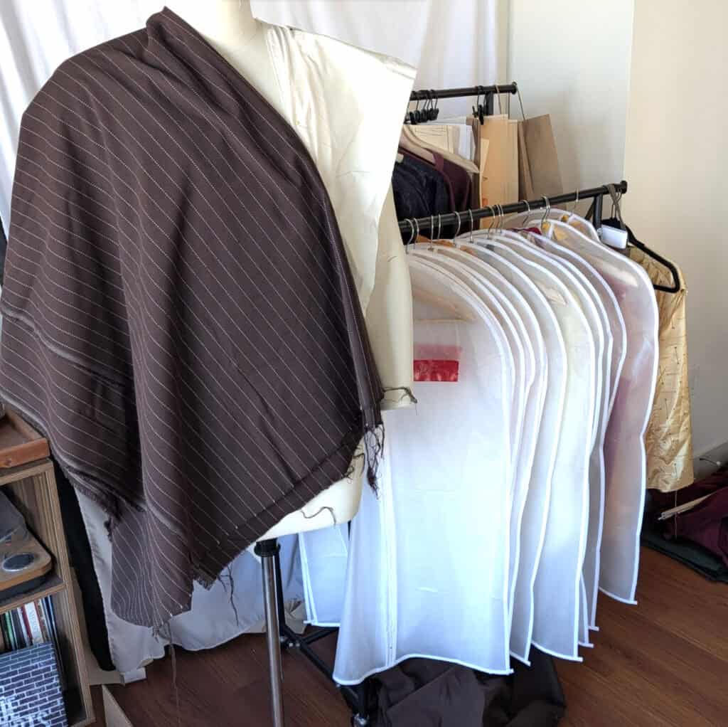 Pinstripe fabric draped on mannequin, showing dark fabric with thin white stripes.